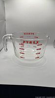 Left profile of Pyrex measuring cup showing handle, spout and red graduations