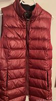 front view of burgundy down vest on hanger