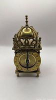 Front view of brass lantern clock showing Roman numeral dial and ornate fretwork