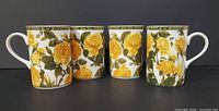 Front angled view showing all four mugs with yellow rose design and handles