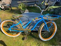 Full side view of blue Electra cruiser bicycle with orange rims and front rack