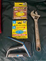 Arrow staple gun, two boxes of staples, Fuller adjustable wrench displayed together