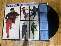 Front cover, inner sleeve and black vinyl record displayed on wooden surface