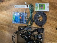 Overview of all items laid out: power bar, extension cord, two sealed cable packs, black RCA cable, box of adapters