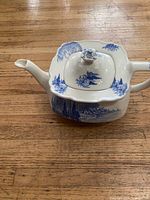 Side view of teapot showing square body, spout, handle and blue transfer pattern