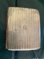 Front of ribbed metal cigarette case showing monogram