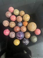 All 22 clay marbles grouped on black surface