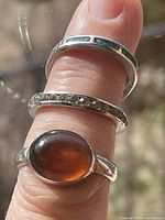 Three sterling rings on finger showing cabochon, marcasite band, and inlay band