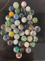 Group of 46 assorted glass marbles on black surface