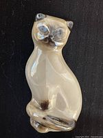 Full view of Siamese cat brooch on dark background