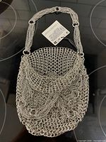 Front view of silver mesh purse showing tag and chain strap
