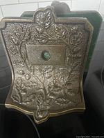 Front angle showing raised oak leaf and acorn pattern and green felt center plug