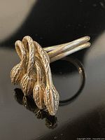 Angled view showing sterling silver ring with five bud-shaped terminals and double band