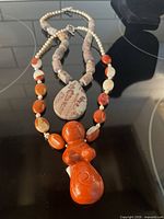Both jasper and pearl necklaces laid out showing pendants and strands