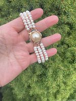Full bracelet laid on hand showing three pearl strands and clasp