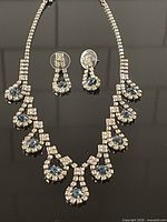 Full view of necklace and earrings on black background