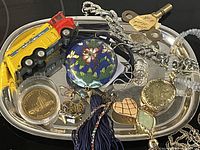 Overview of entire lot on silver tray showing jewellery, coin, key, toy truck