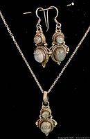 Full view of necklace with pendant and matching earrings displayed on black form