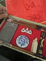 Open case showing full contents: two brushes, inkstone, ink stick, seal stamp, porcelain pot, brush rest