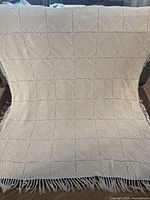 Full view of cream crochet bedspread draped to show size and fringe