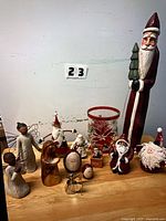 Group shot of all angel statues, Santa figurines, decorative eggs and candle holder on table