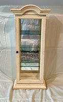 Front view of blond wood cabinet with glass door closed