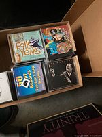 Open banker box showing top layer of CDs including The Folk Years and others