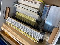 Box containing stacked legal pads, note pads, index cards