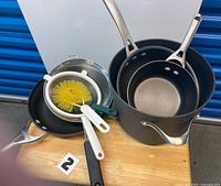 Nonstick stock pot, pans, strainers, dish brush displayed