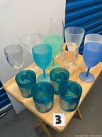 Assorted plastic tumblers and stemmed glasses displayed on small table