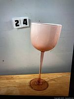 Single pink long-stem wine glass next to lot number