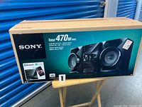 Front of sealed retail box showing Sony MHC-ECL77BT system and features