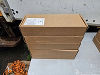 Stack of four sealed brown cartons of cable management arm kits