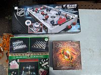 Front view of three boxed games on table: NHL All Star hockey, Lucky Seven Gaming Classics, Trivial Pursuit LOTR