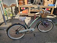 Left side view of green Electra step-through cruiser with basket, showing floral fenders, chainguard and overall condition