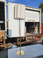 Full view of gold-tone floor lamp on table