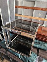 Angled view showing top and lower smoked glass shelves within chrome frame