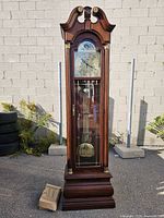 full frontal view of grandfather clock showing case, pediment and glass door