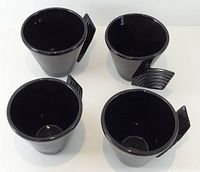 Top view of four black cups showing interior glaze and handle shape