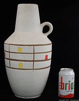 Full view showing vase front with grid and colored squares next to soda can for scale