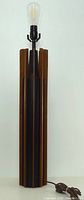 Full view of tall teak and black ceramic lamp with bulb