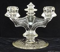 Front view showing double arms, candle cups, finial, and base