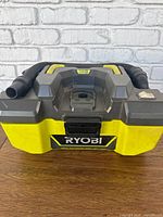 Front view of vacuum showing Ryobi logo, battery bay, hose, exterior condition