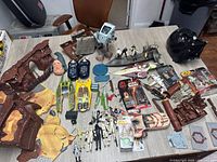 Overview of assorted Star Wars playset pieces, ships, figures, accessories and mask on tabletop