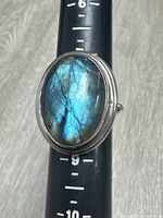 Front view showing oval iridescent gemstone and size gauge