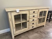 Front view of buffet showing glass doors, center drawers, hardware and overall finish