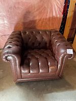 Front angled view of tufted leather club chair showing overall design and wear