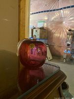 Red glass apple paperweight on table