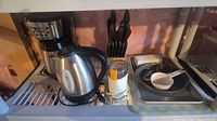 Overall view showing coffee maker, electric kettle, knife block, utensils, cookware