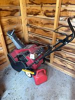 Snow blower and fuel can in shed corner